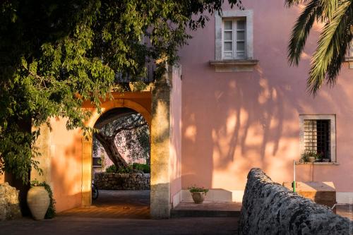 een ingang naar een roze gebouw met een boog bij Masseria Degli Ulivi in San Corrado di Fuori