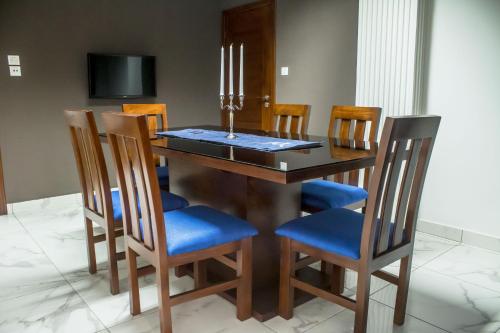 a dining room table with blue chairs and a television at Residence Maryka II in Cotonou