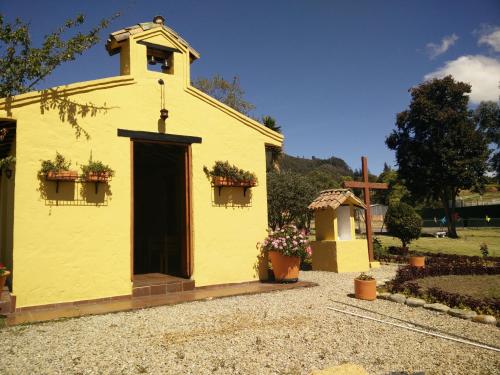 a small yellow church with a cross in a yard at Hotel Campestre Franchesca in Tabio