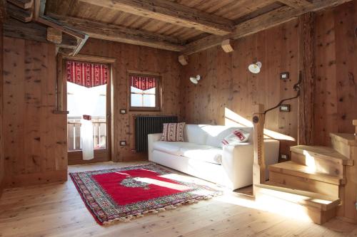 a living room with a white couch and wooden walls at Chalet Del Cuore Guesthouse in Valdisotto
