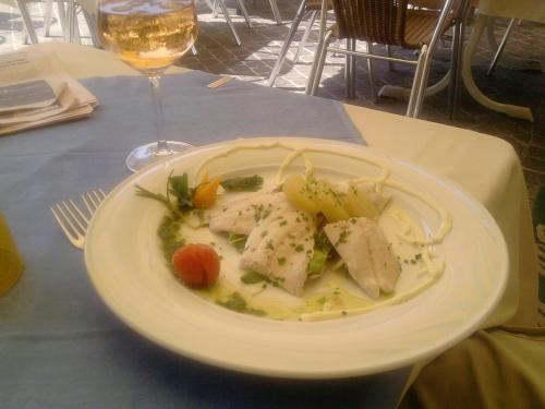 a plate of food on a table with a glass of wine at Locanda San Marco in Torri del Benaco