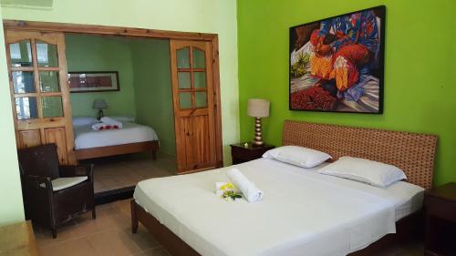 a bedroom with a bed with a painting on the wall at Beau Vallon Bungalows in Beau Vallon