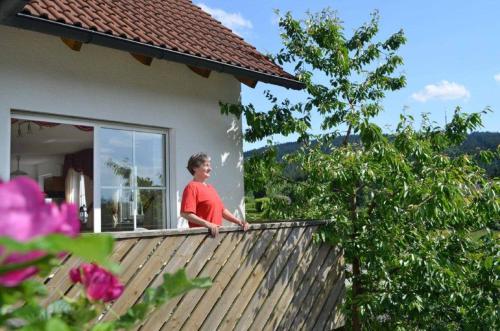 a woman standing on the balcony of a house at Ferienwohnung Hopfennest in Bischofsgrün