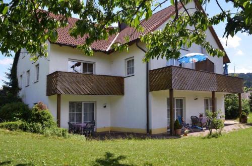 a white house with a dog sitting in the window at Ferienwohnung Hopfennest in Bischofsgrün