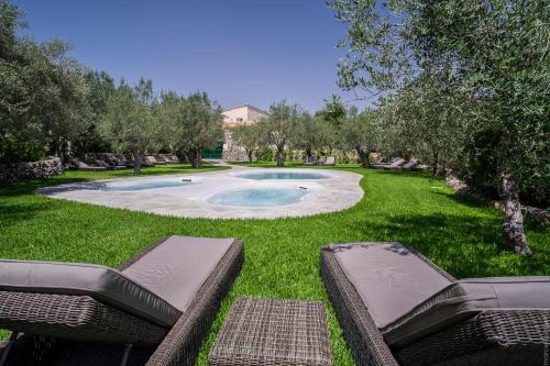 a swimming pool in a yard with two chairs at Masseria Degli Ulivi in San Corrado di Fuori