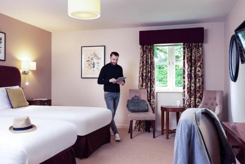 a man standing in a hotel room with two beds at Mercure Thame Lambert Hotel in Chinnor