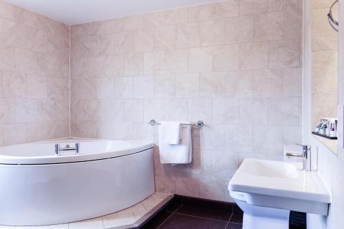 a bathroom with a tub and a toilet and a sink at Mercure Thame Lambert Hotel in Chinnor