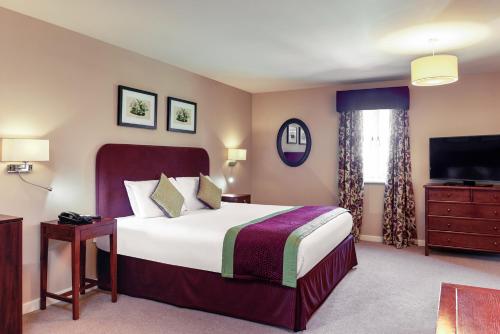 a bedroom with a large bed and a large window at Mercure Thame Lambert Hotel in Chinnor