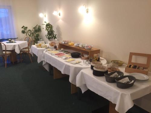 a long table with white table cloths and food on it at Hotel garni Zur Mühle in Angermünde