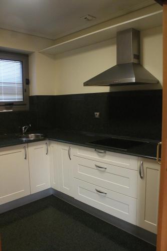 a kitchen with white cabinets and a stove top oven at Santiago Apartments Bilbao in Bilbao
