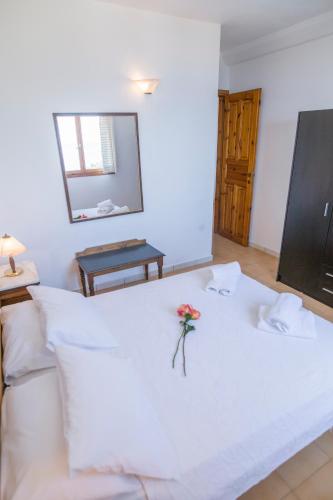 a white bed with a flower on top of it at Corfu Aqua Nisaki in Nisakion