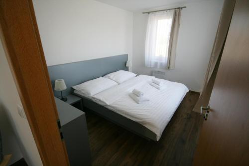a bedroom with a bed with two towels on it at Apartmány Apollon Resort Lednice in Lednice