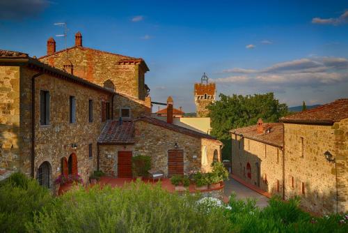 a group of stone buildings with a castle in the background at Tenuta Lupinari in Bucine