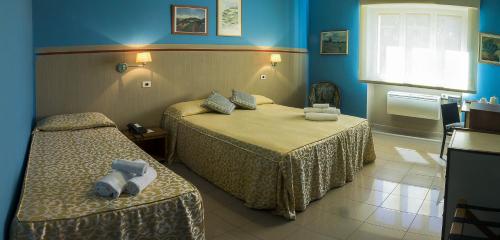 una camera d'albergo con due letti e pareti blu di Hotel Plaza a Taranto