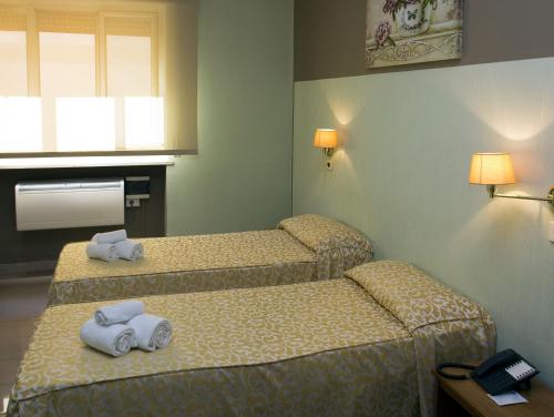 two beds in a hotel room with towels on them at Hotel Plaza in Taranto