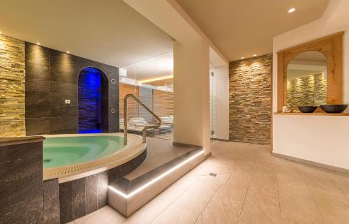 a bathroom with a large tub with a window at Hotel Rosskopf in Vipiteno