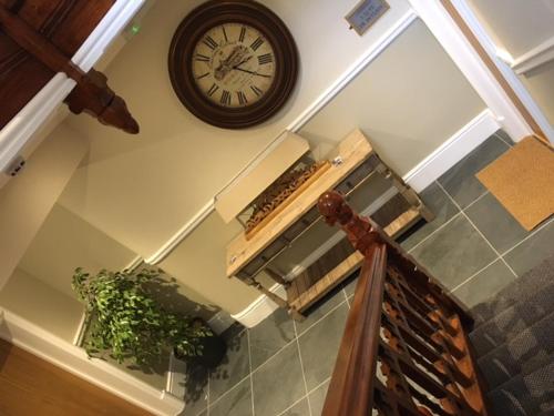 a clock on the wall next to a staircase at Llys y Dderwen - Oak Court in Aberystwyth