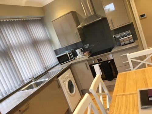 a kitchen with a sink and a stove and a table at Llys y Dderwen - Oak Court in Aberystwyth