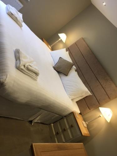 a bedroom with a bed with white sheets and pillows at Llys y Dderwen - Oak Court in Aberystwyth
