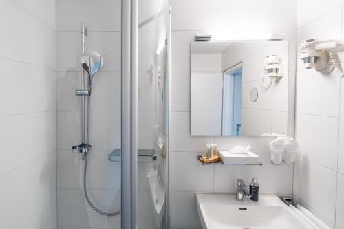 a white bathroom with a shower and a sink at Hotel Hohberg "Next to BBC Arena" in Schaffhausen