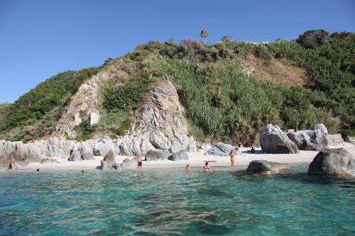 a group of people on a beach with rocks at Residence Porto Ulisse in Parghelia