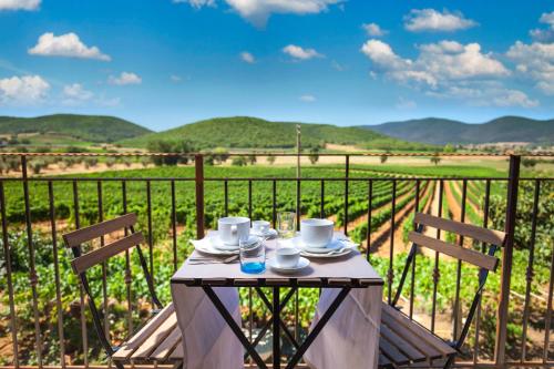 a table with cups and saucers on top of a balcony at Poggiolivi Agriturismo Bio in Maremma in Alberese