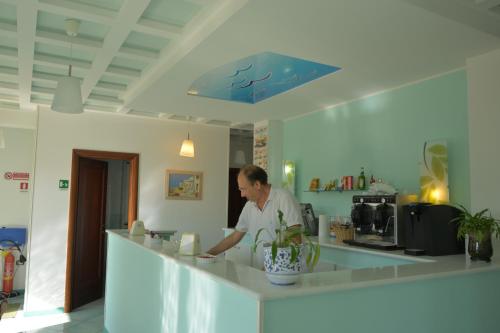 a man standing at a counter in a kitchen at Larus Hotel in Sangineto