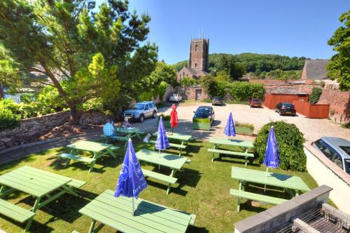 a group of picnic tables and blue umbrellas at Dunster Castle Hotel in Dunster