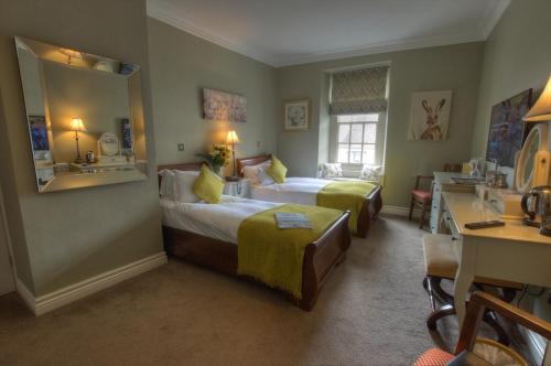 a hotel room with two beds and a desk at Dunster Castle Hotel in Dunster
