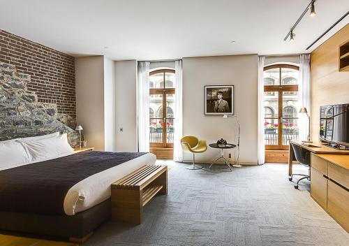 Dormitorio con cama, escritorio y TV en Hotel Gault en Montreal