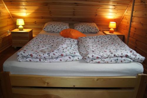 a bed in a wooden room with two lamps at Grzywaczówka in Przesieka