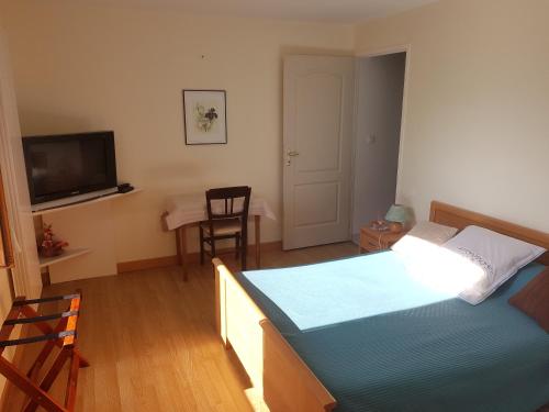 een slaapkamer met een bed en een televisie en een tafel bij Hôtel Ducret in Champfromier