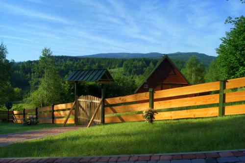 a wooden fence with a gazebo in a field at Grzywaczówka in Przesieka