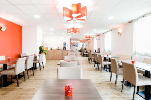 une salle à manger avec des tables et des chaises blanches dans l'établissement Dios Hotel, à Bruguières