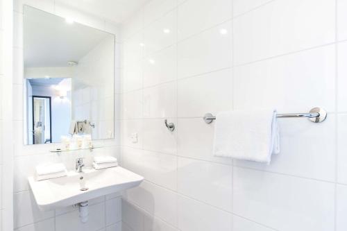 a white bathroom with a sink and a mirror at Dios Hotel in Bruguières