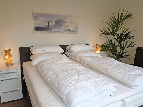 a bed with white sheets and pillows on it at Toms Kajute in Heiligenhafen