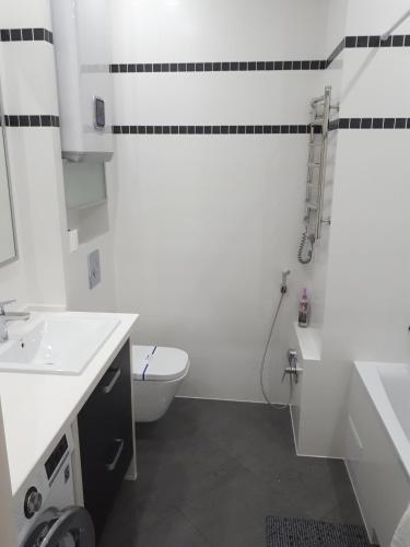 a white bathroom with a toilet and a sink at IRIS apartments in Odesa