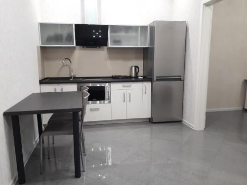 a kitchen with a table and a stainless steel refrigerator at IRIS apartments in Odesa