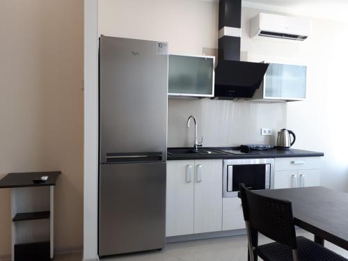 a kitchen with a stainless steel refrigerator and a table at IRIS apartments in Odesa