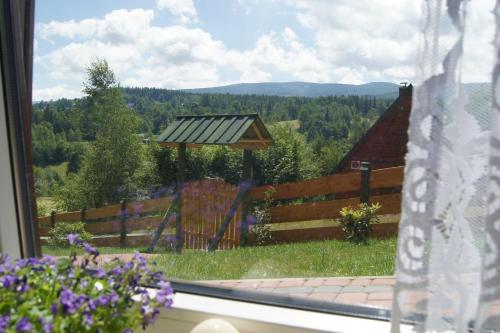 a window view of a garden with a wooden fence at Grzywaczówka in Przesieka