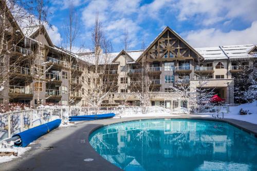 una piscina del complejo en la nieve frente a un edificio en The Aspens by Whistler Premier, en Whistler