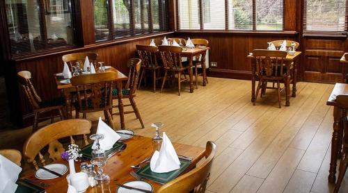 un restaurante con mesas y sillas de madera y ventanas en Round Tower Hotel, en Ardmore