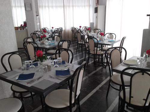 ein Esszimmer mit Tischen und Stühlen mit blauen Servietten in der Unterkunft Kardamili Beach Hotel in Kardhamili