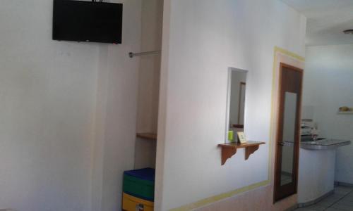 a room with a television on a white wall at Hotel Sarabi in Barra de Navidad