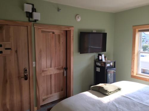 a bedroom with a bed and a tv and a door at Roam Inn in Munising