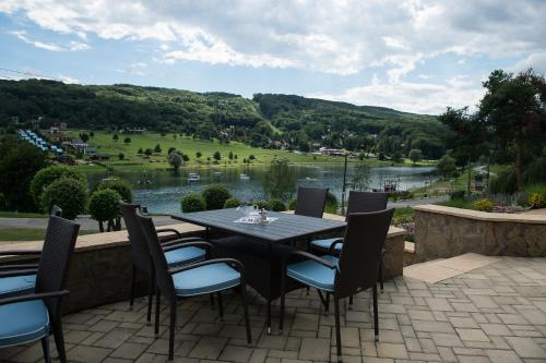 a table and chairs on a patio with a view of a lake at Garden Hotel Domaša in Domaša Dobrá