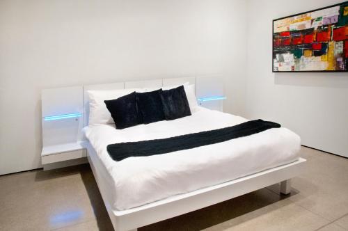 uma cama branca com almofadas pretas em cima em The Cube em Cowichan Bay