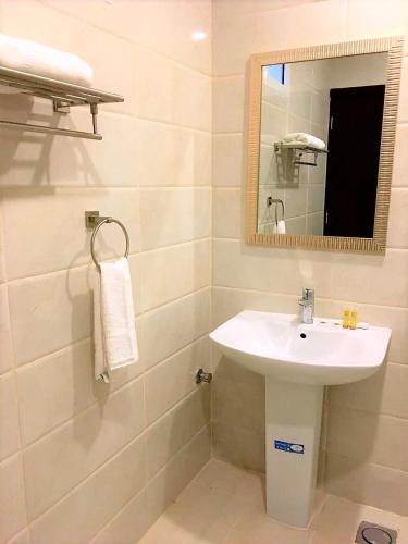 a bathroom with a white sink and a mirror at Towlan Al Rawdah تولان للشقق المخدومة فرع الروضة in Riyadh