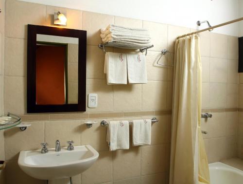 a bathroom with a sink and a mirror and towels at Huerta Grande Cabañas in Huerta Grande