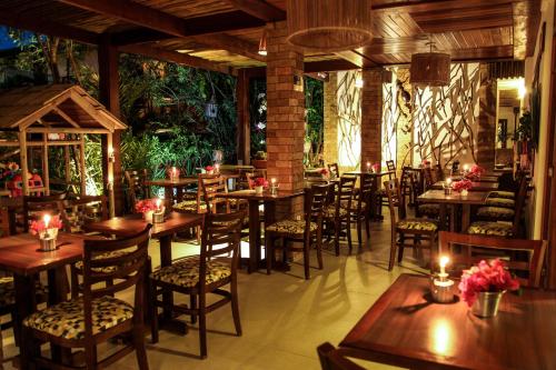 a restaurant with wooden tables and chairs and plants at Pousada João Sol in Praia do Forte